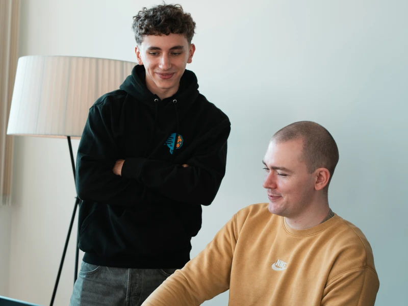 Daniel Goncharov und Konstantin Auffinger. Daniel steht und Konstantin sitzt. Auf dem Tisch steht ein aufgeklappter Laptop in den beide schauen.