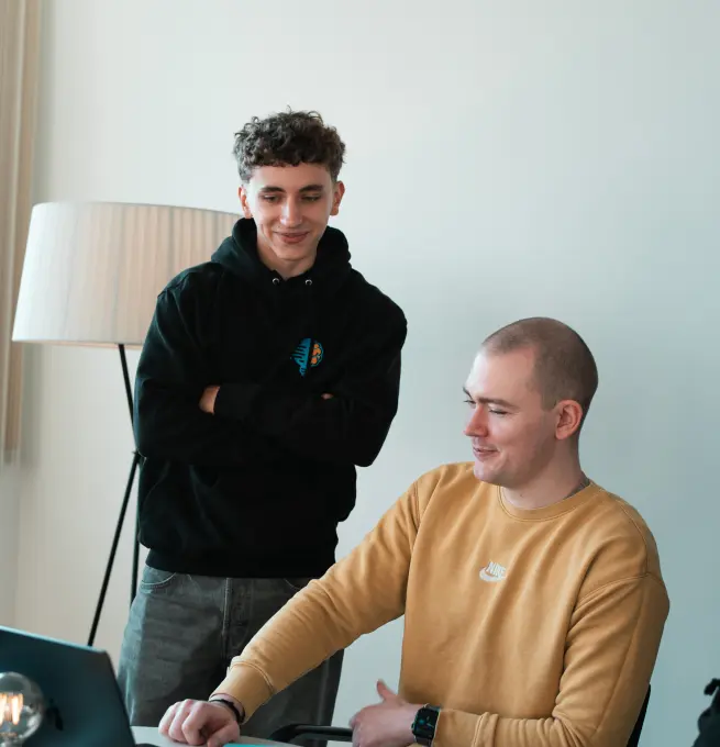 Daniel Goncharov und Konstantin Auffinger. Daniel steht und Konstantin sitzt. Auf dem Tisch steht ein aufgeklappter Laptop in den beide schauen.