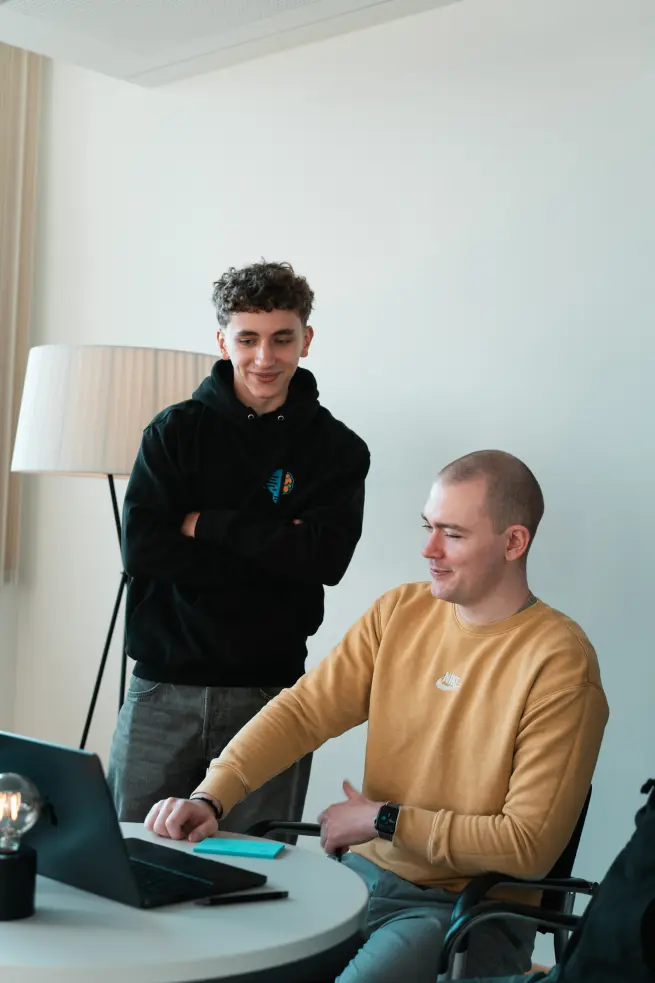 Daniel Goncharov und Konstantin Auffinger. Daniel steht und Konstantin sitzt. Auf dem Tisch steht ein aufgeklappter Laptop in den beide schauen.