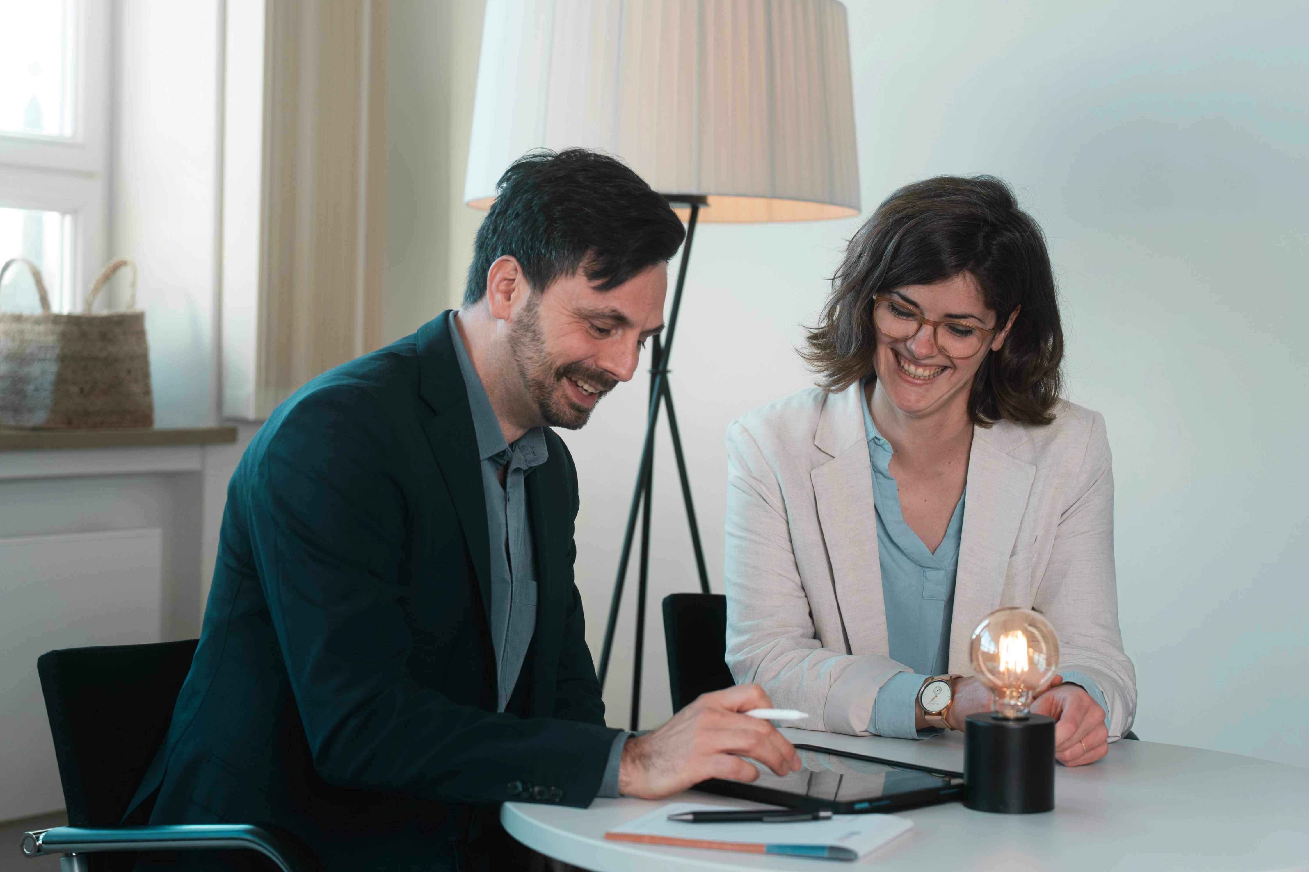Florian Bobek mit einem Kunden. Beide sitzen an einem runden Tisch. Auf dem Tisch ist ein Ipad, ein Block mit InnoBrain Logo sowie Stift und einer Lampe.
