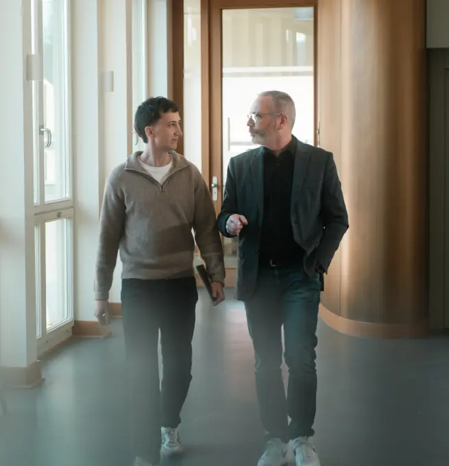 Tobias Reuss mit einem Kunden. Sie laufen einen Gang entlang.