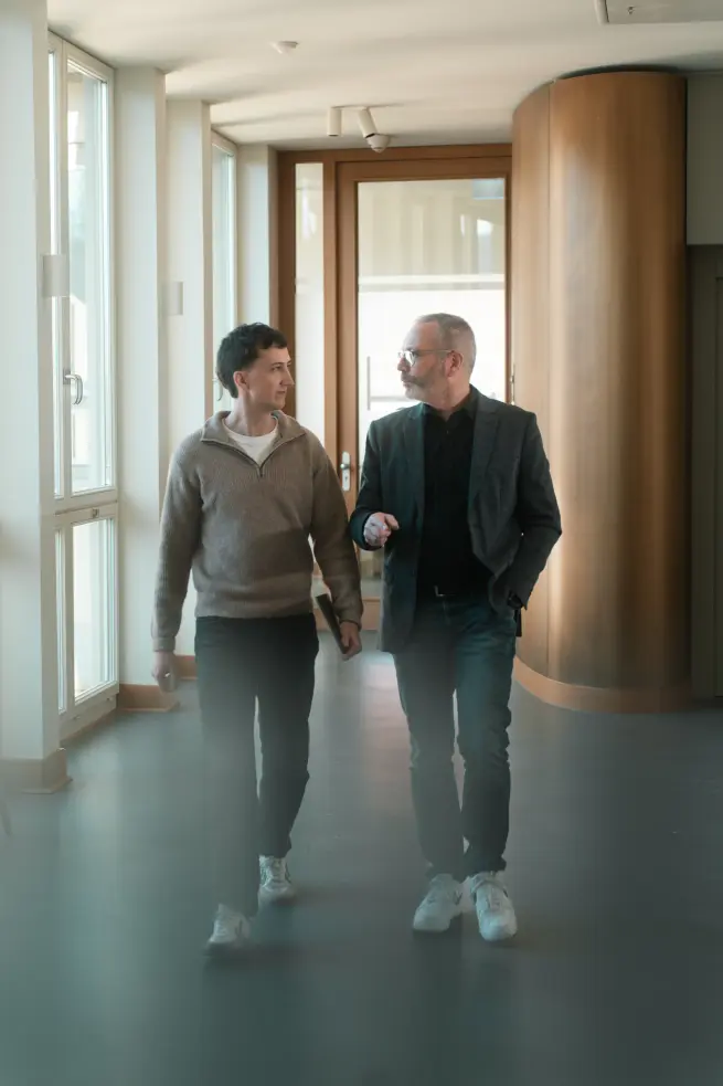 Tobias Reuss mit einem Kunden. Sie laufen einen Gang entlang.